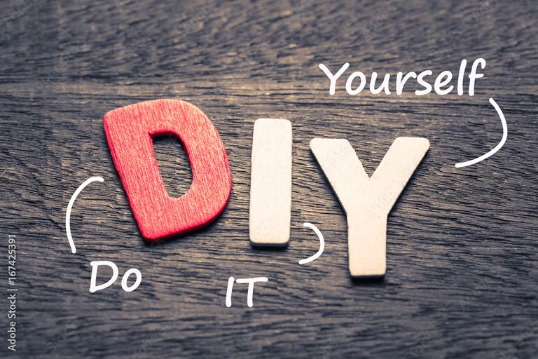 Wooden block letters spelling 'DIY' on a dark wood surface, with handwritten labels reading 'Do It Yourself.'